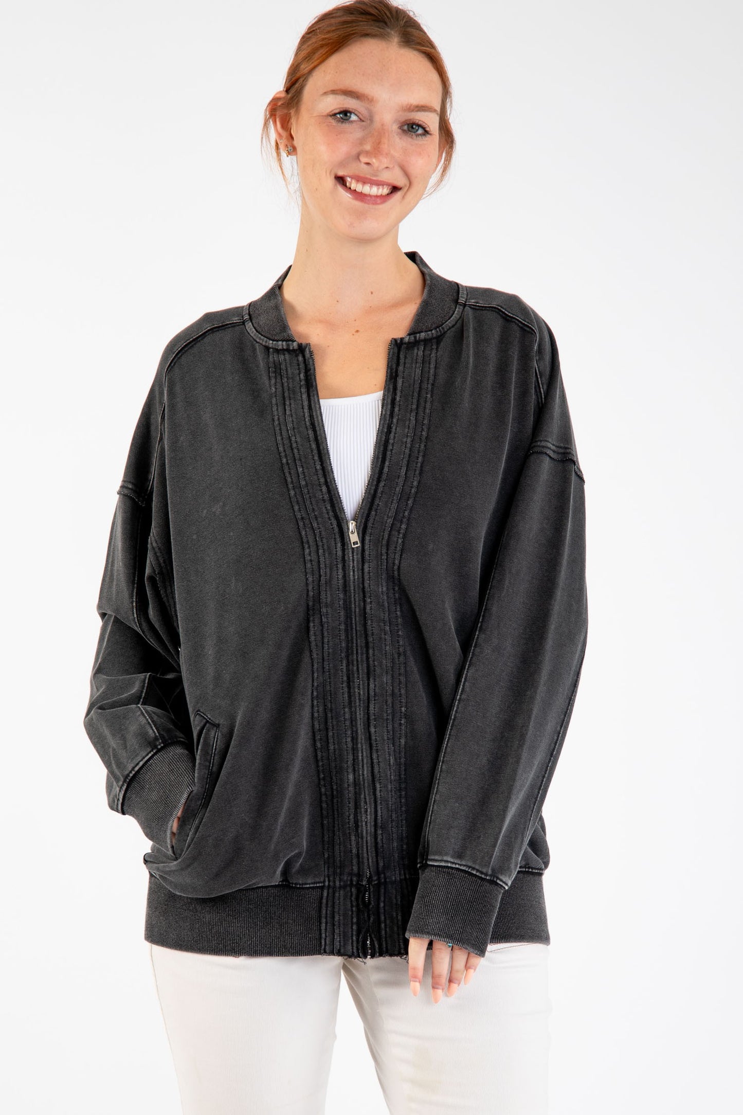 Woman wearing Birdie Washed Cotton Exposed Seam Bomber Jacket with zipper closure and side pockets